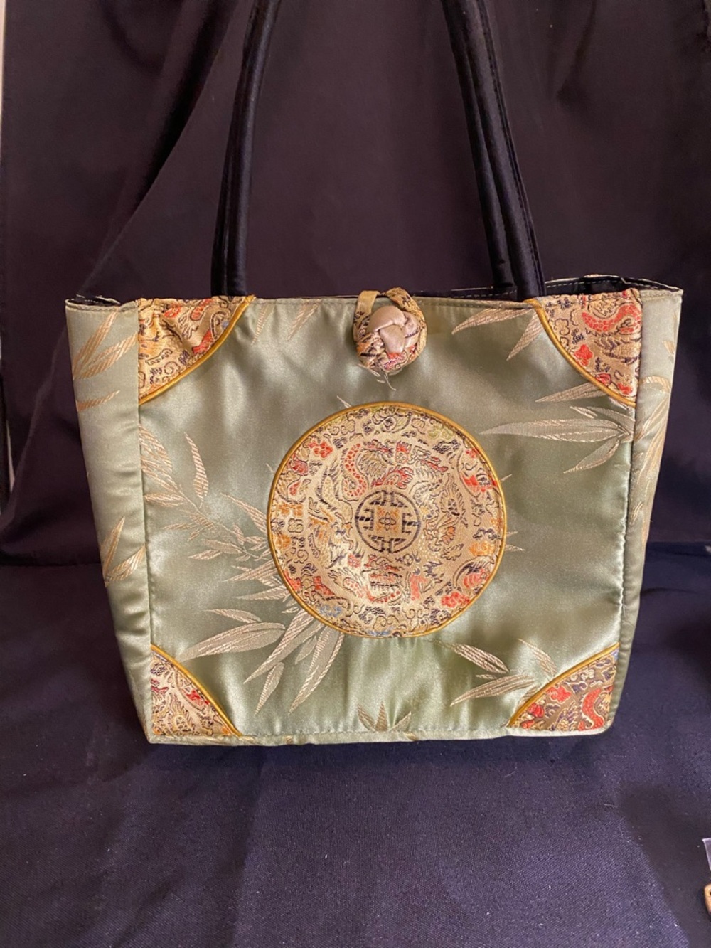 Vintage silk tote with medallion design,black handles, & a knot/loop closure.